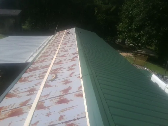 Old rusted panels beside newly installed green metal roofing — Wind Damage Roof Repair by Roofing Brothers in La Verkin