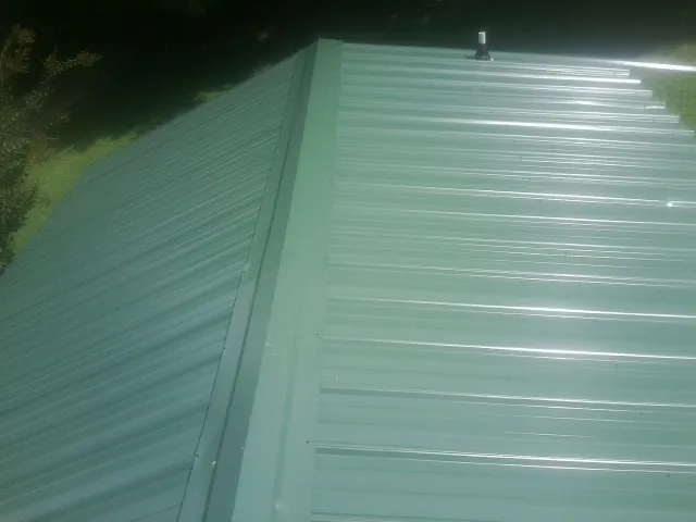 New green metal panels meeting at the ridge of a roof — Flat Roof Repair work by our crew in La Verkin