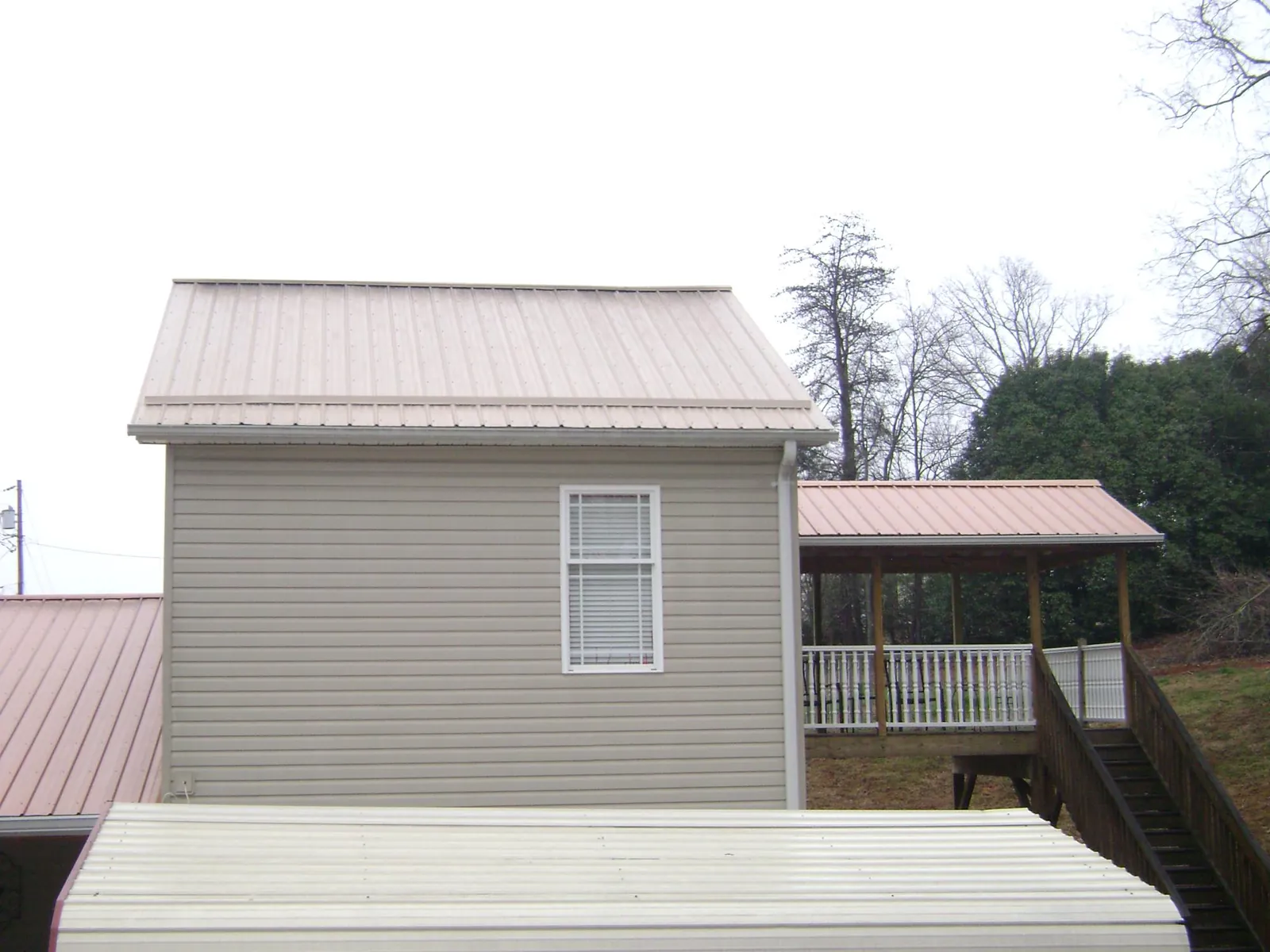 Tan metal roofs on a two story addition and attached porch, from a Roof Replacement job in La Verkin